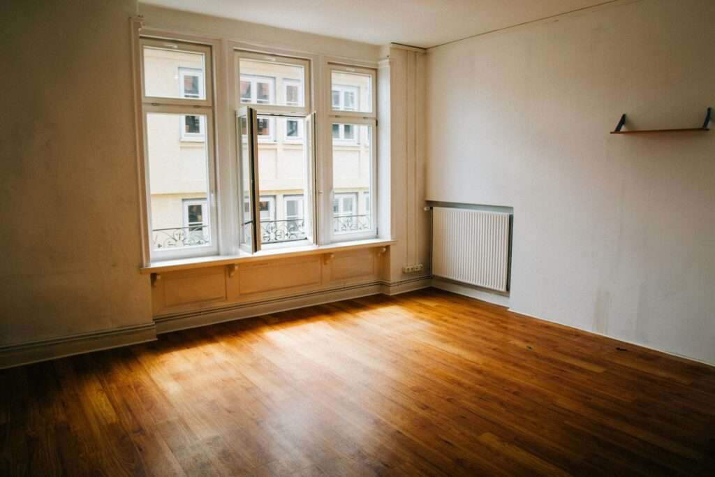 Tomt rum med trägolv och stort fönster